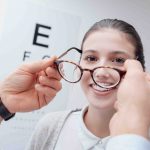 Young happy woman trying her new pair of glasses after the eye exam